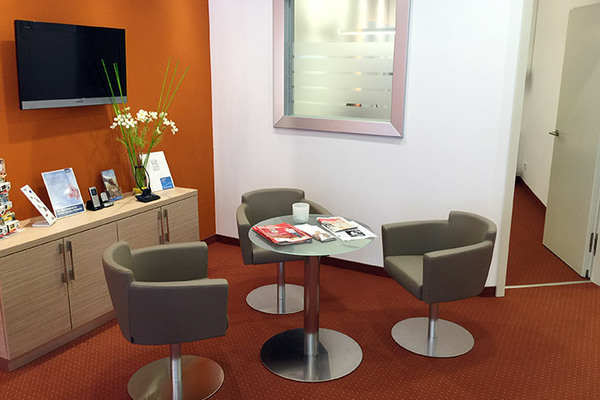 Heller Wartebereich mit modernen Sesseln, Tisch, Zeitschriften und Dekoration in Büro.